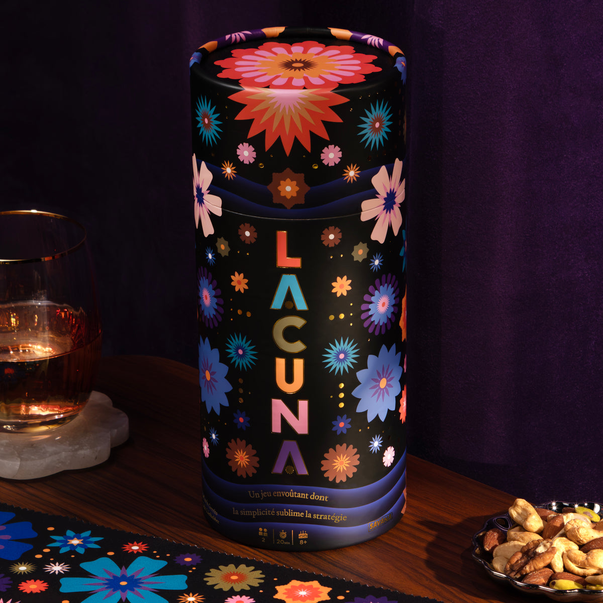 La boîte de Lacuna posée sur une table, à côté du tapis de jeu fleuri